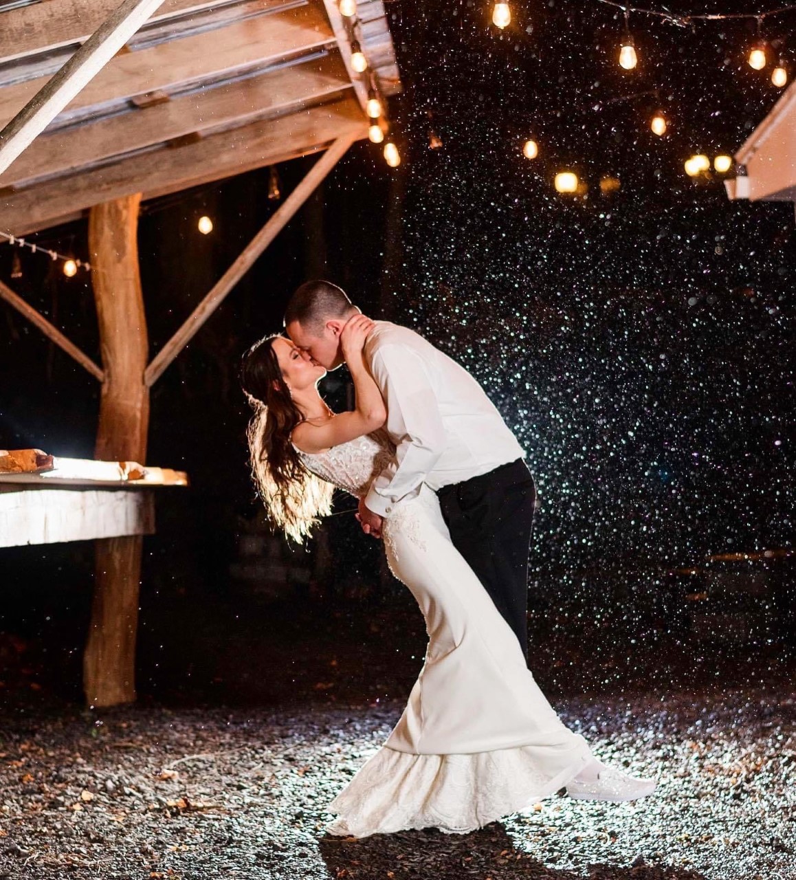 Bride and groom outdoors kissing in the night as it snows