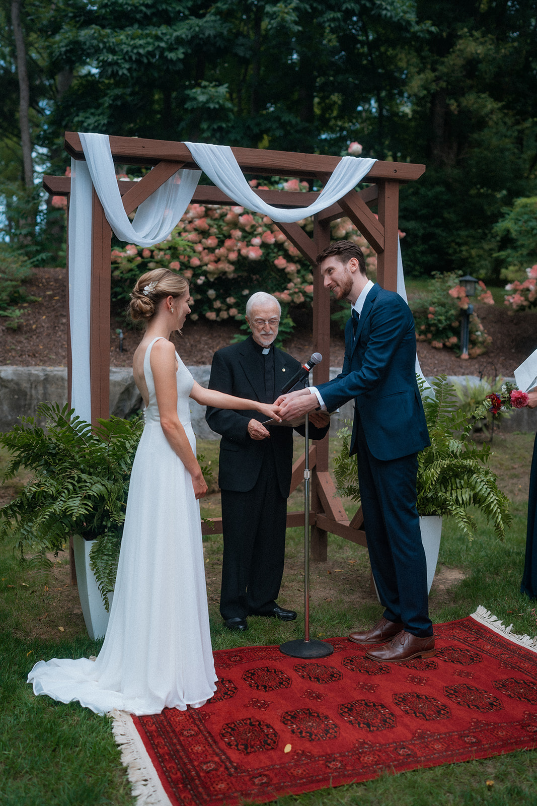 Bride and groom exchanging rings in their outdoor wedding ceremony in the Grove at Springside Inn