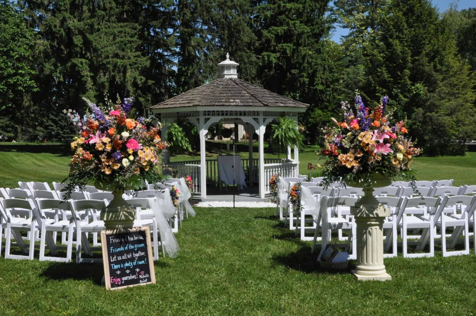 Colorful flowers and bright white chairs surround the front lawn gazebo